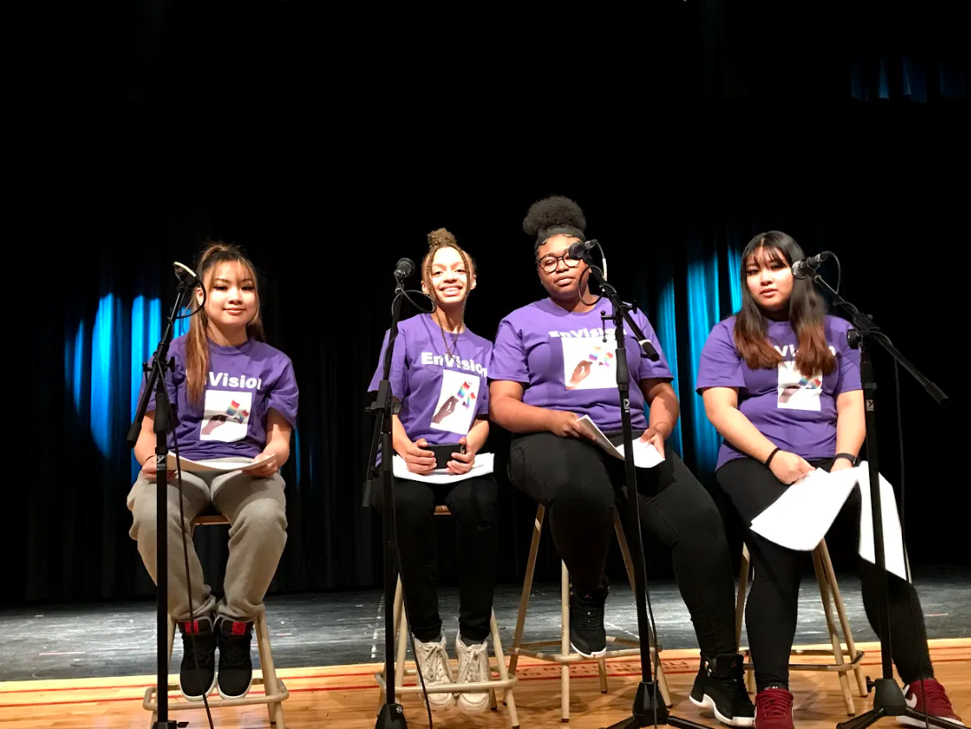 Four female students sit on stage with microphones at the Envision Conference