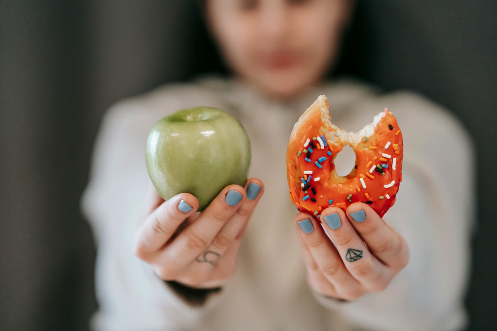 Person holding donut and apple