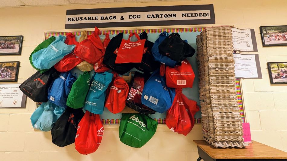 Display of reusable bags and egg cartons students collected in school hallway.