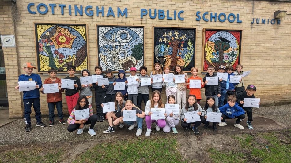 Students stand in front of Cottingham Public School with certificates of acknowledgement presented from Avenue Road Food Bank.
