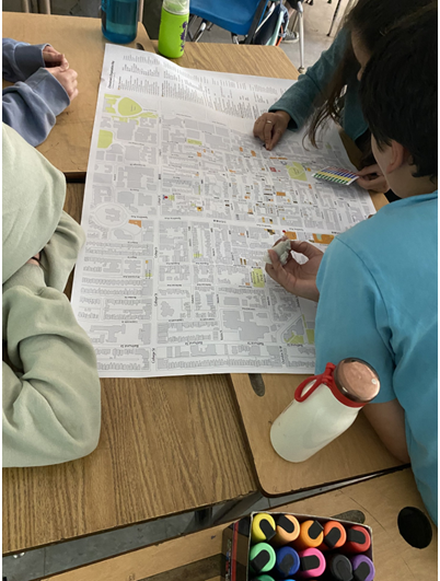 Image 2: Three students review a map of Chinatown and use stickers to pinpoint locations they feel positively or negatively about.