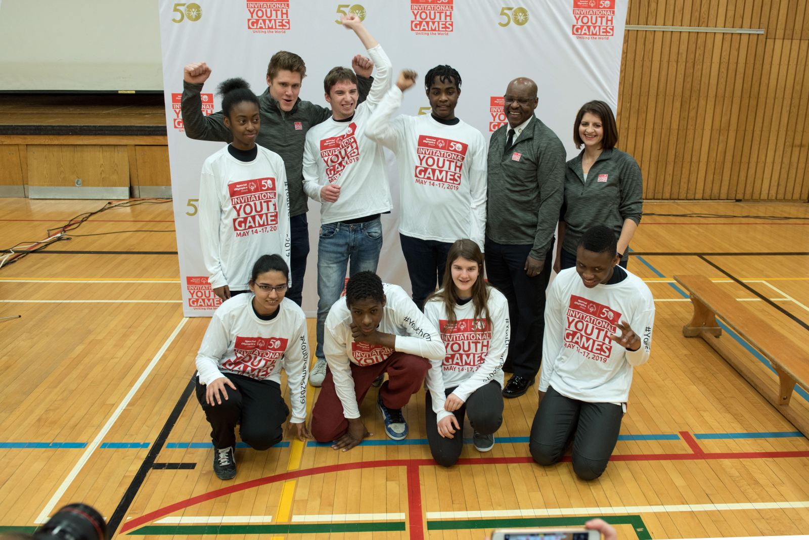 7 Students and 3 adults posing in front of a branded backdrop for the Invitational Youth Games