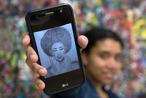 A student holds up a phone with an image of Black woman on it