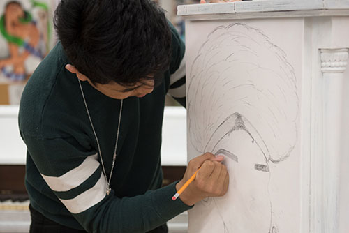 A student sketches an outline of a woman with an afro