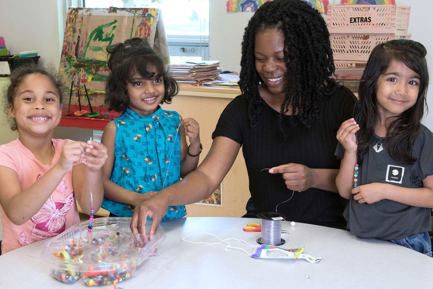 Three students and educator doing activity with beads