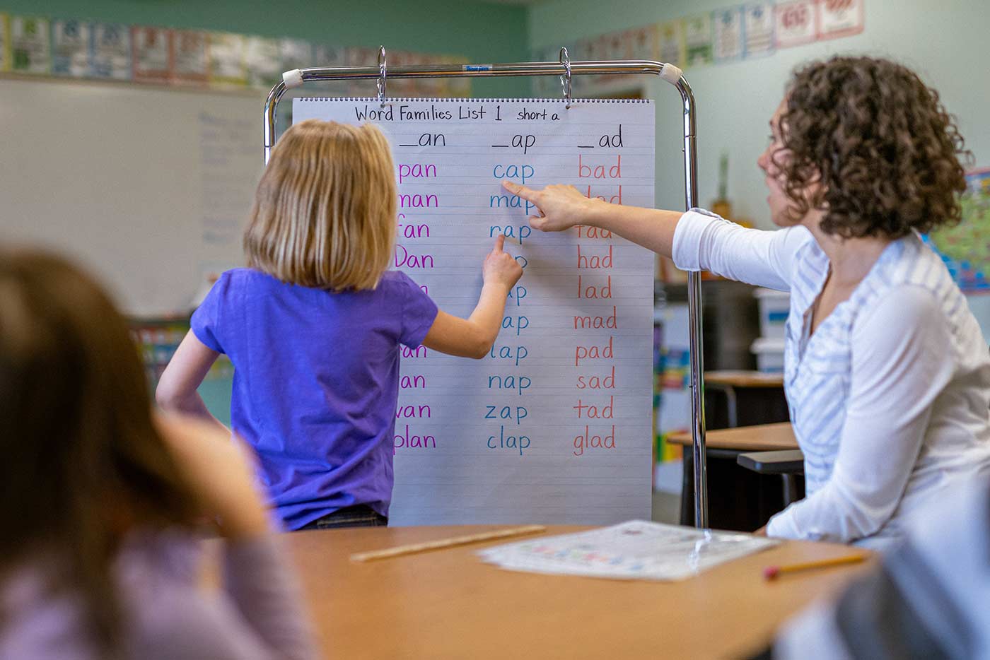 Teacher pointing to chart paper as student reads aloud