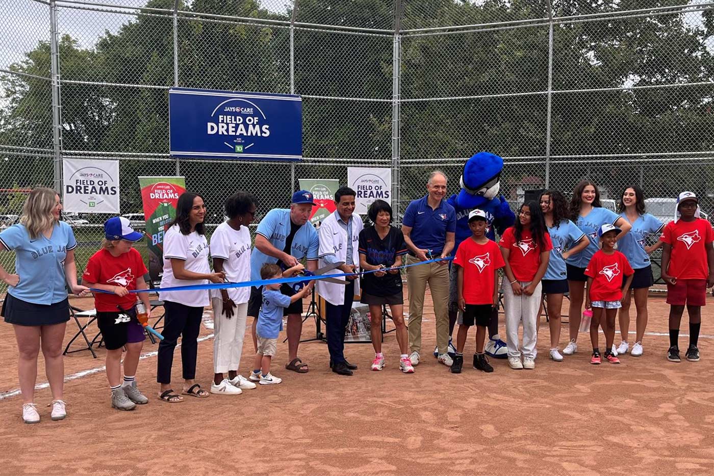 TDSB staff, students, government partners pose for a ribbon cutting photo at the new baseball diamond at Eastview PS