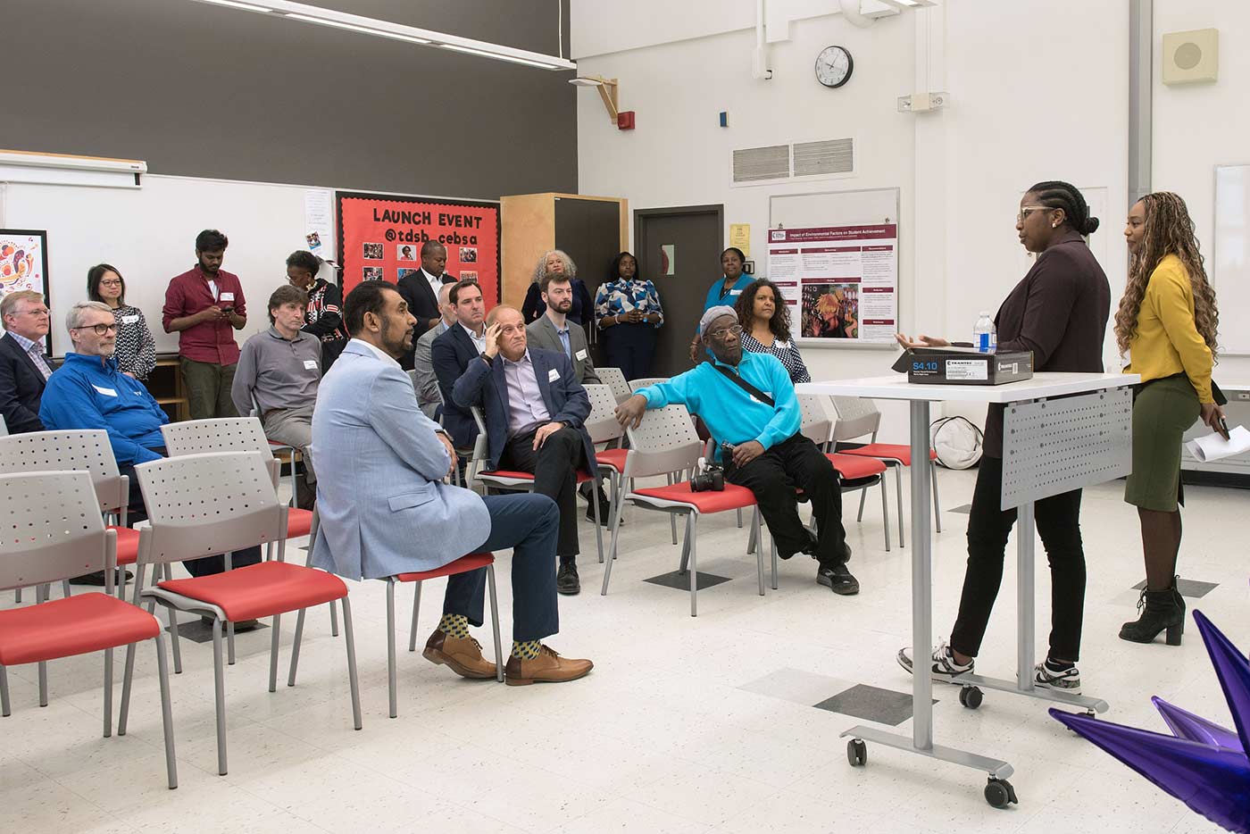 Several TDSB staff members sitting and standing in a room in discussion